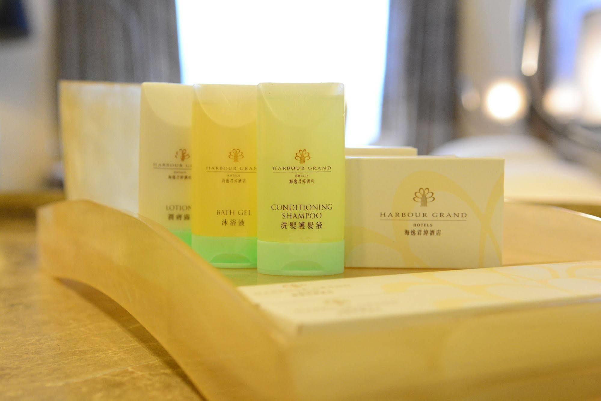 Harbour Grand Hong Kong Hotel Exterior photo The photo shows a selection of personal care products arranged on a wooden tray. There are three small bottles in various colors: one yellow, one green, and one yellowish-green, labeled as "Conditioning Shampoo" and "Shampoo." Additionally, there is 